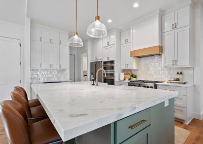 Textured tile, polished marble, and warm metallic accents elevate this bright, functional kitchen centered around a sleek custom wood range hood.