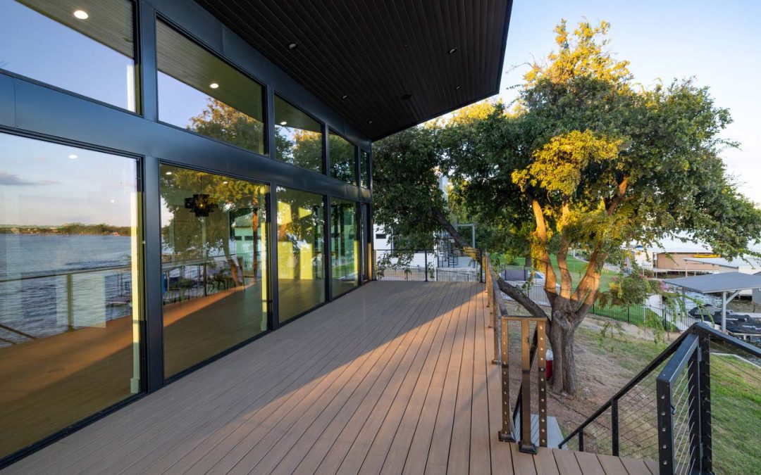 Custom home builder Granite Shoals modern lakefront deck with glass walls, metal railing, and elevated outdoor living space.