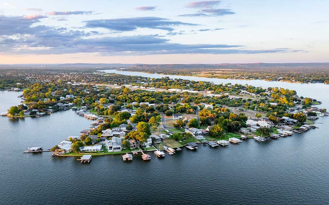 Lake LBJ Custom Home Builder aerial view showing waterfront homes, private boat docks, and surrounding Hill Country terrain.